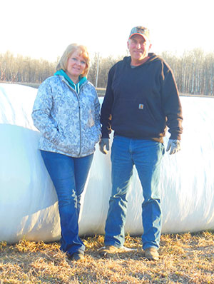 Ernie and Linda Johnson with wrapped hay bales